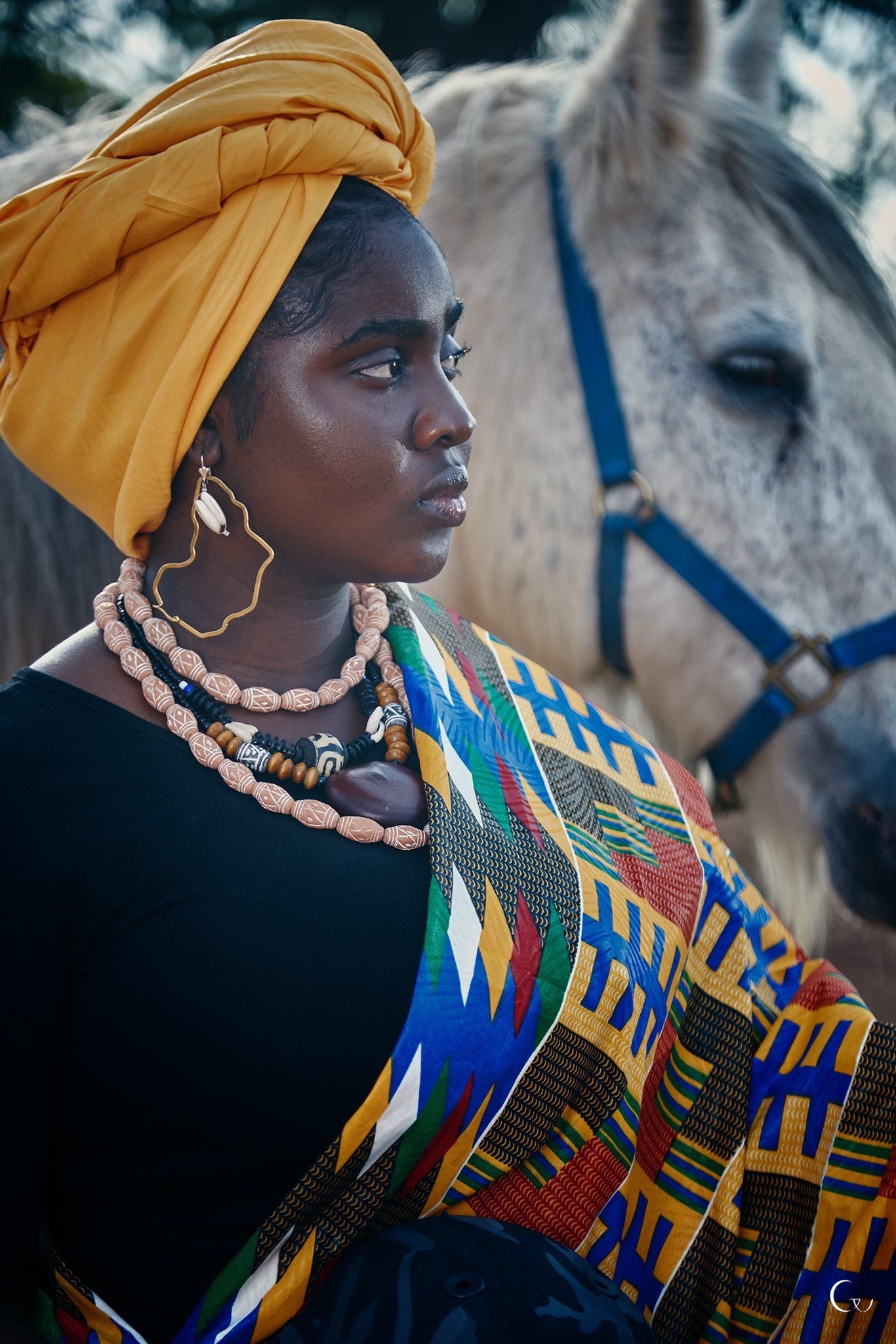 Aisha Ahmad Suleiman in kente cloth beside a grey horse